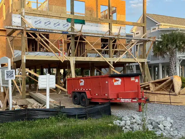 Low-wall dump trailer being loaded with construction debris on a Southport NC driveway