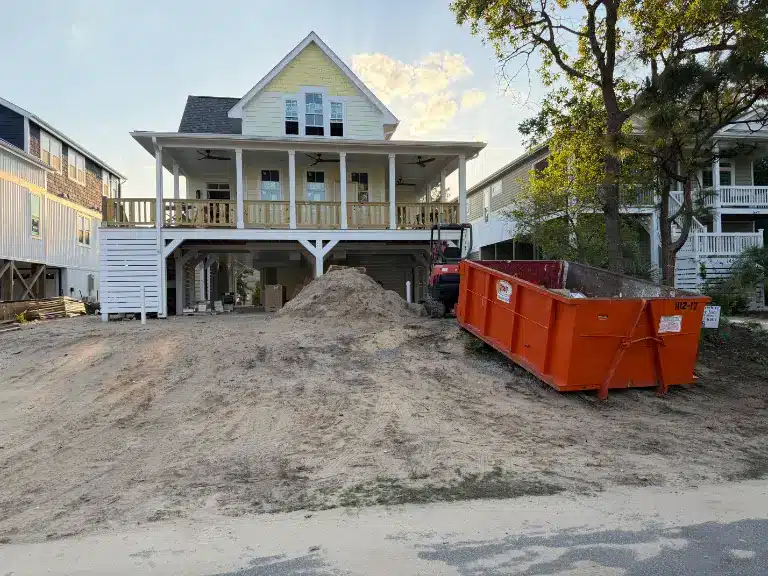 Roll-off dumpster delivered to a raised beach house on a narrow coastal street near Southport NC